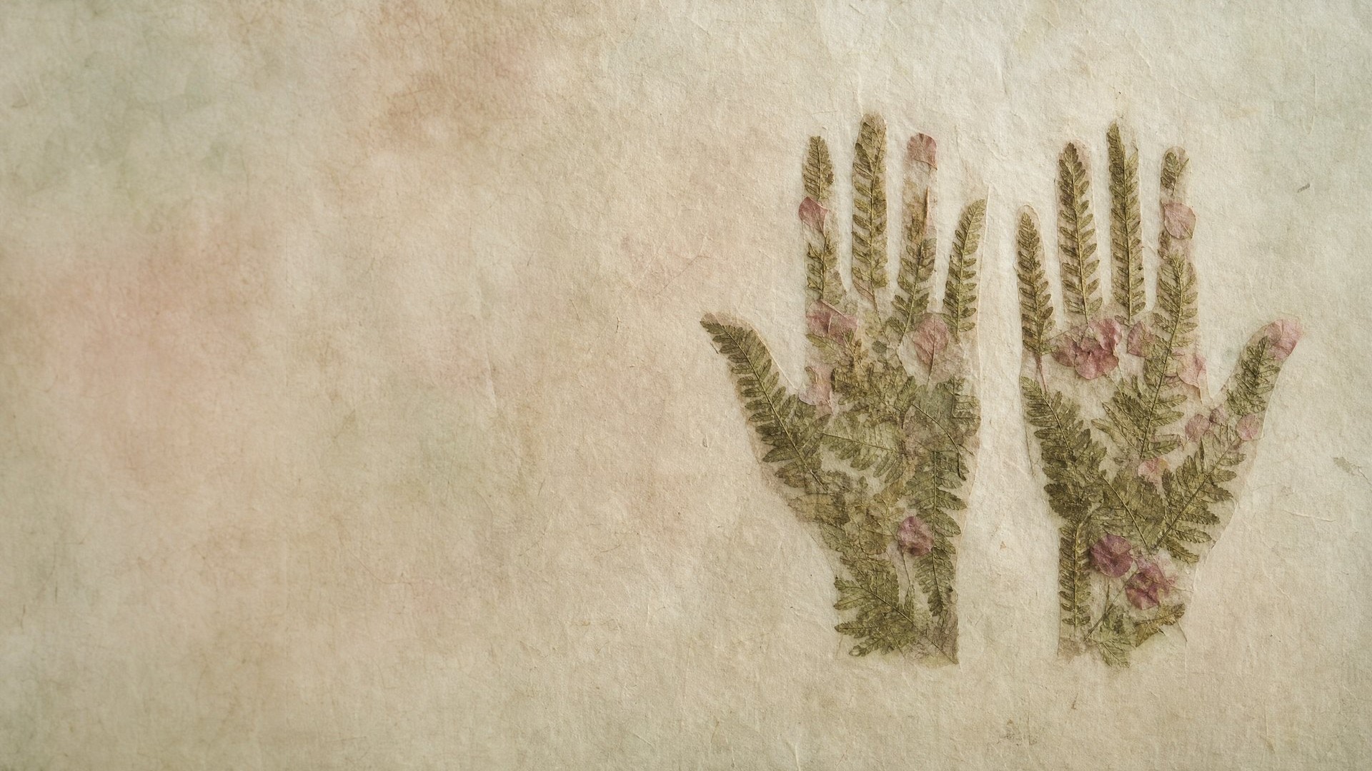 Two hands embroidered in green leaves and pink flowers on pale parchment